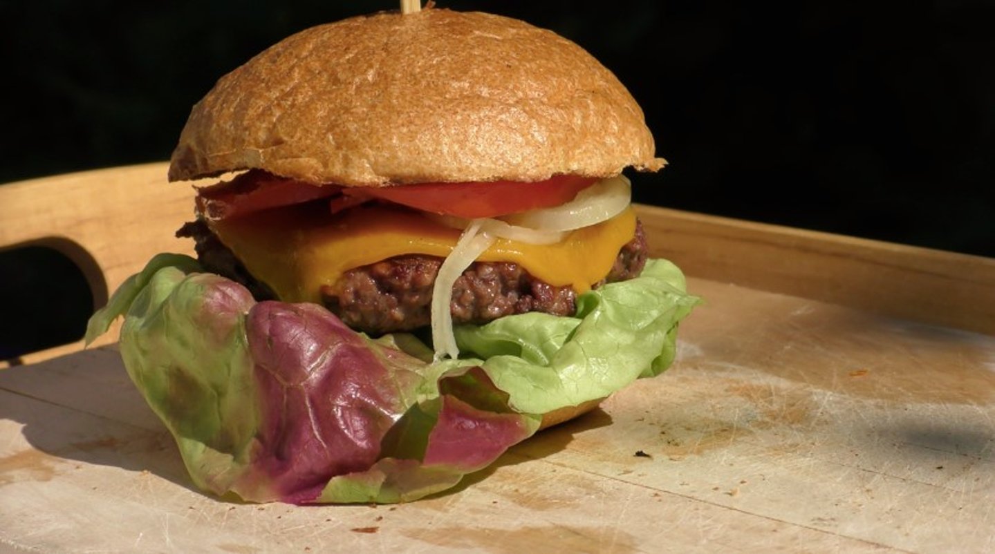 Rezept: Der Bockburger – Ein Burger aus Wildfleisch Bockburger fertig gegrillt und mit Brötchen, Tomate, Zwiebeln, Käse und Salatblatt aufgebaut
