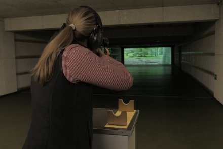 Drückjagdseminare als Weiterbildung für Jungjäger Jungjägerin im Schießkino mit Jagdwaffe im Anschlag.