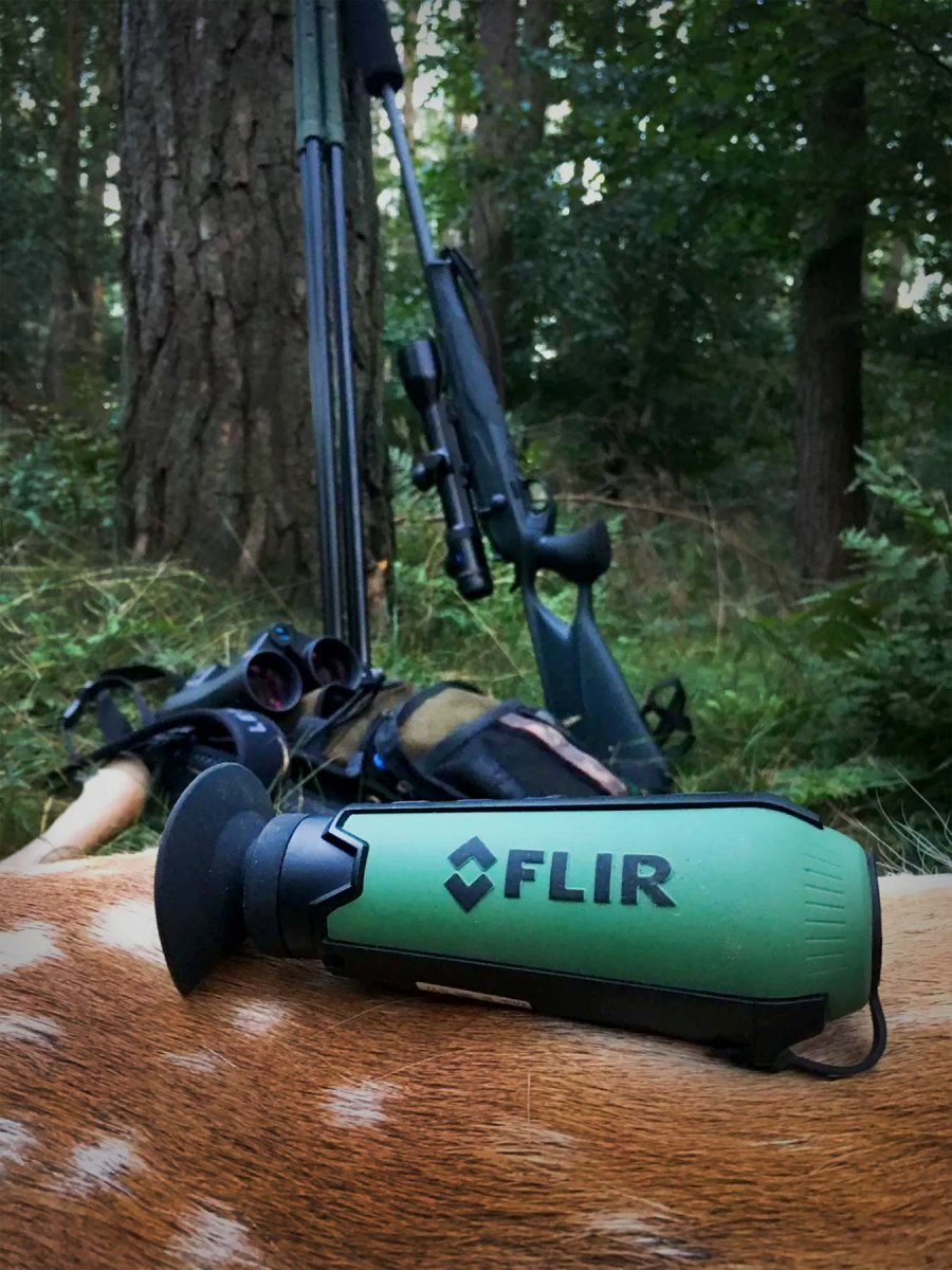 Flir Scout TK Wärmebildkamera für Einsteiger Eine Flir Scout TK Wärmebildkamera für Einsteiger liegt auf dem Fell eines toten Wildes, während im Hintergrund Gewehr und Rucksack zu sehen sind.
