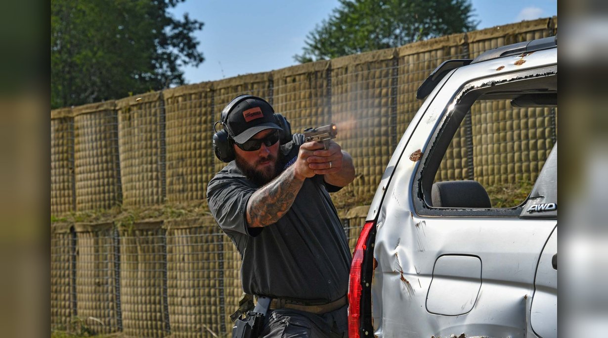 Schütze schießt aus Deckung hinter Auto mit der Pistole SIG Sauer P320-M17