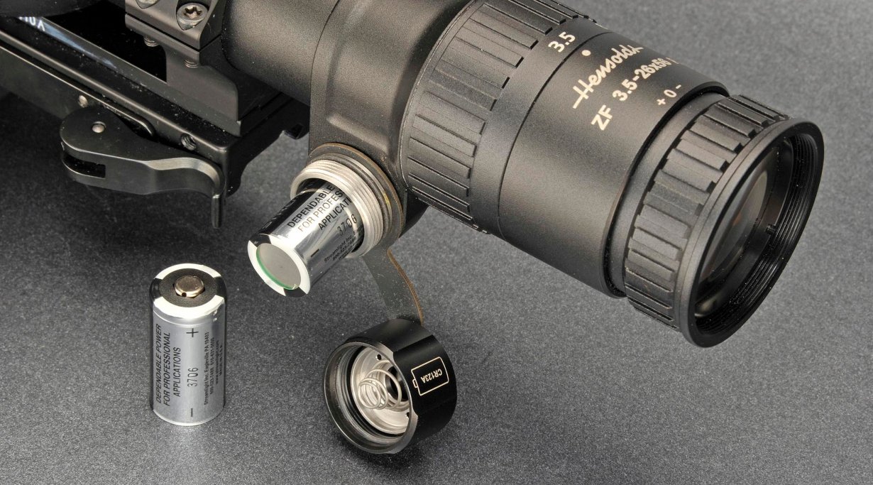 Das Batteriefach, offen, daneben der befestigte Deckel und zwei CR123A-Batterien. 