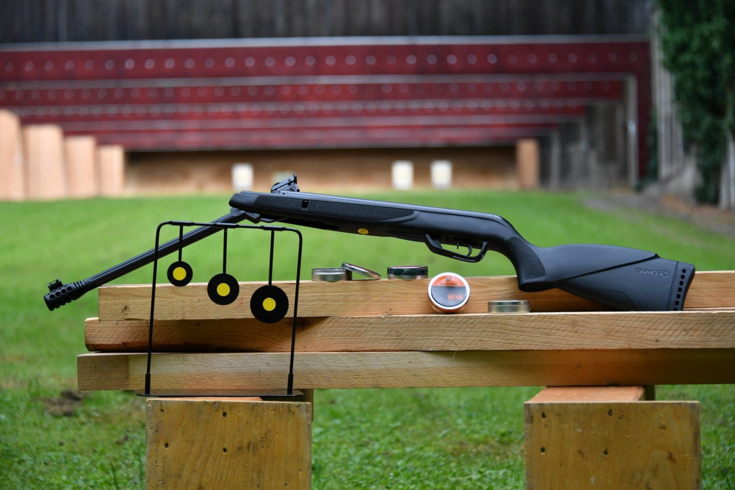 Das Druckluftgewehr GAMO Black Bear im Praxistest GAMO Black Bear Druckluftgewehr geknickt auf einem Schießstand. Darum Dekoration in Form von Zielen.