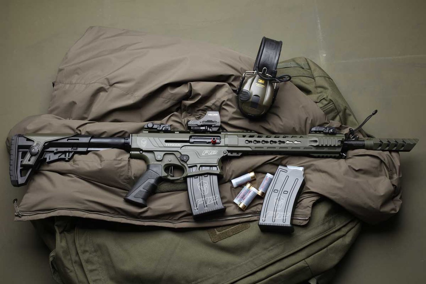 Praxistest: Typhoon F12 Selbstladeflinte im Kaliber 12/76 Selbstladeflinte Typhoon F12 auf AR-15-Basis im Kaliber 12/76 Magnum mit Kastenmagazin, Patronen und Gehörschutz