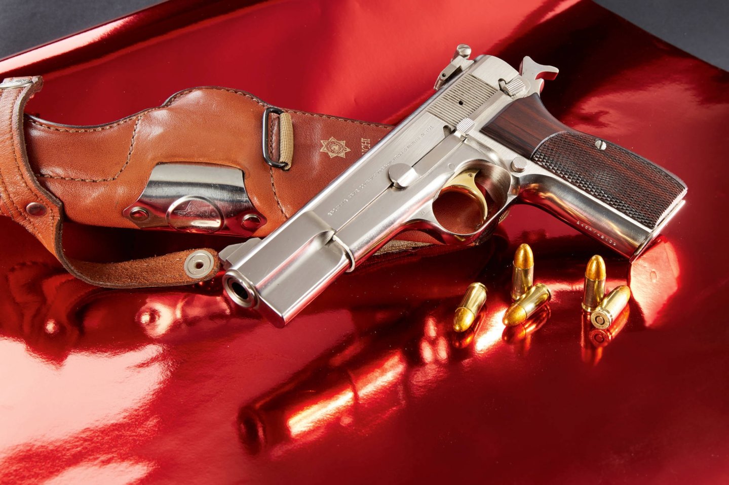 Youngtimer & Golden Girls: Geschichte und Technik der Browning High Power Nickel Selbstladepistole  Browning High Power Nickel Sport Pistole mit Patronen und Lederholster auf rotem Untergrund