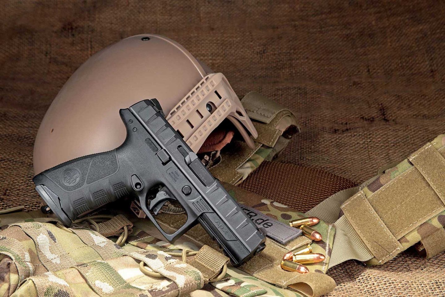 Test & Technik: Beretta APX in 9 mm Luger Beretta APX auf U.S.-Army Kleidung drappiert mit Helm im Hintergrund.