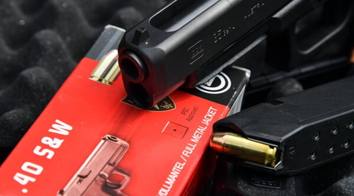 Mündung und Laufpartie der Polymerpistole GLOCK 35 MOS neben Magazin und Munition