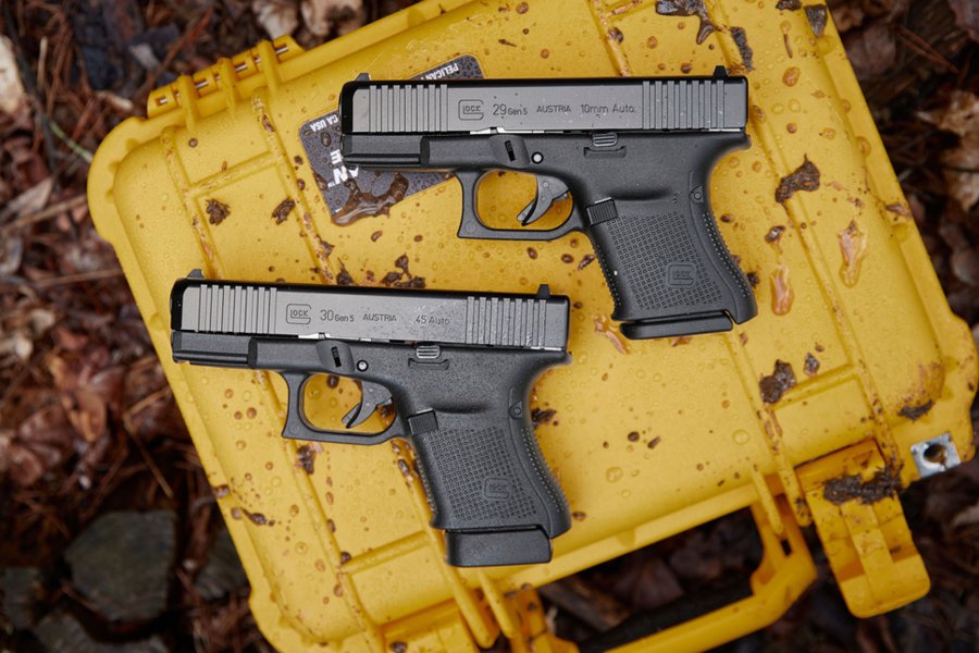Neue Polymerpistolen von GLOCK: G49 Gen5 MOS in 9 mm Luger, G29 Gen5 in 10 mm Auto und G30 Gen5 in .45 Auto Die Neue GLOCK G29 mit der G 30 zusammen auf einem gelben Transportkoffer.