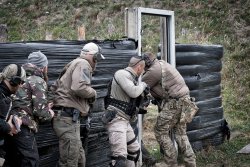 3. International Bodyguard Conference 2018 4 Teilnehmer stehen an einer Mauer aus Autoreifen, einer stürmt durch einen Türrahmen.