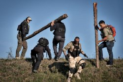 3. International Bodyguard Conference 2018 Die Teilnehmer tragen Baumstämme einen Hang hinauf.
