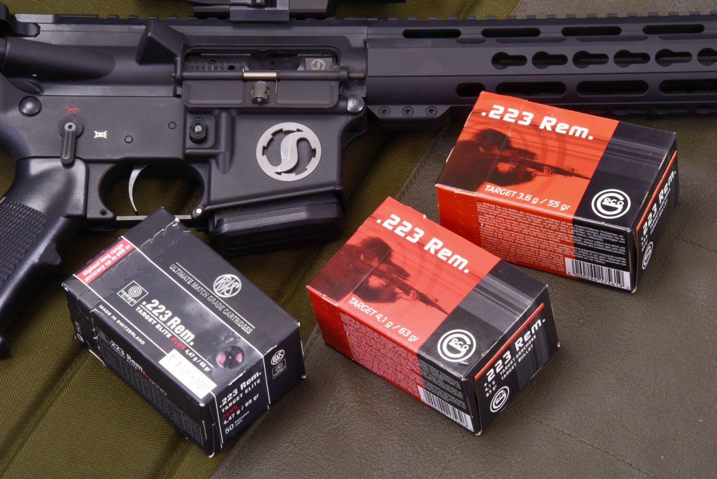 Kaliber .223 Rem GECO und RWS Munition mit Gewehr im Hintergrund.