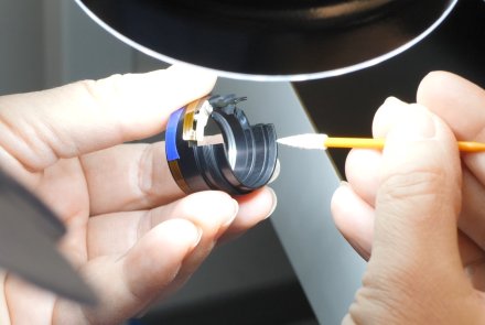 Wie entsteht ein MINOX Zielfernrohr? Ein Mitarbeiter bearbeitet mit einem Tupfer die innere Optik des Minox ZP Zielfernrohrs.