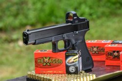 GECO Open Red Dot Sight auf dem Prüfstand GLOCK 34 Gen5 MOS mit montiertem GECO Open Red Dot Sight und einigen Schachteln GECO Hexagon.