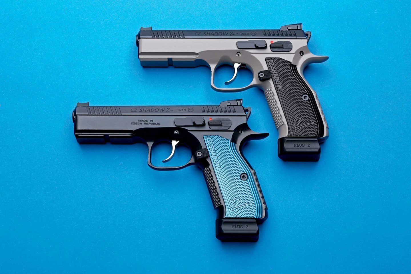 caliber 10/2016 CZ Shadow 2 in Stahl-Optik (oben) und schwarz mit blauer Griffschale (unten) auf blauem Hintergrund.