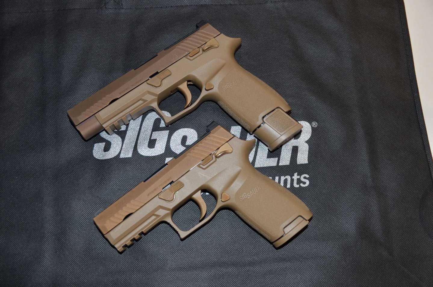 caliber 4/2017 Zwei SIG Sauer P 320 in linker Seitenansicht liegen auf einer SIG Sauer-Rangebag.