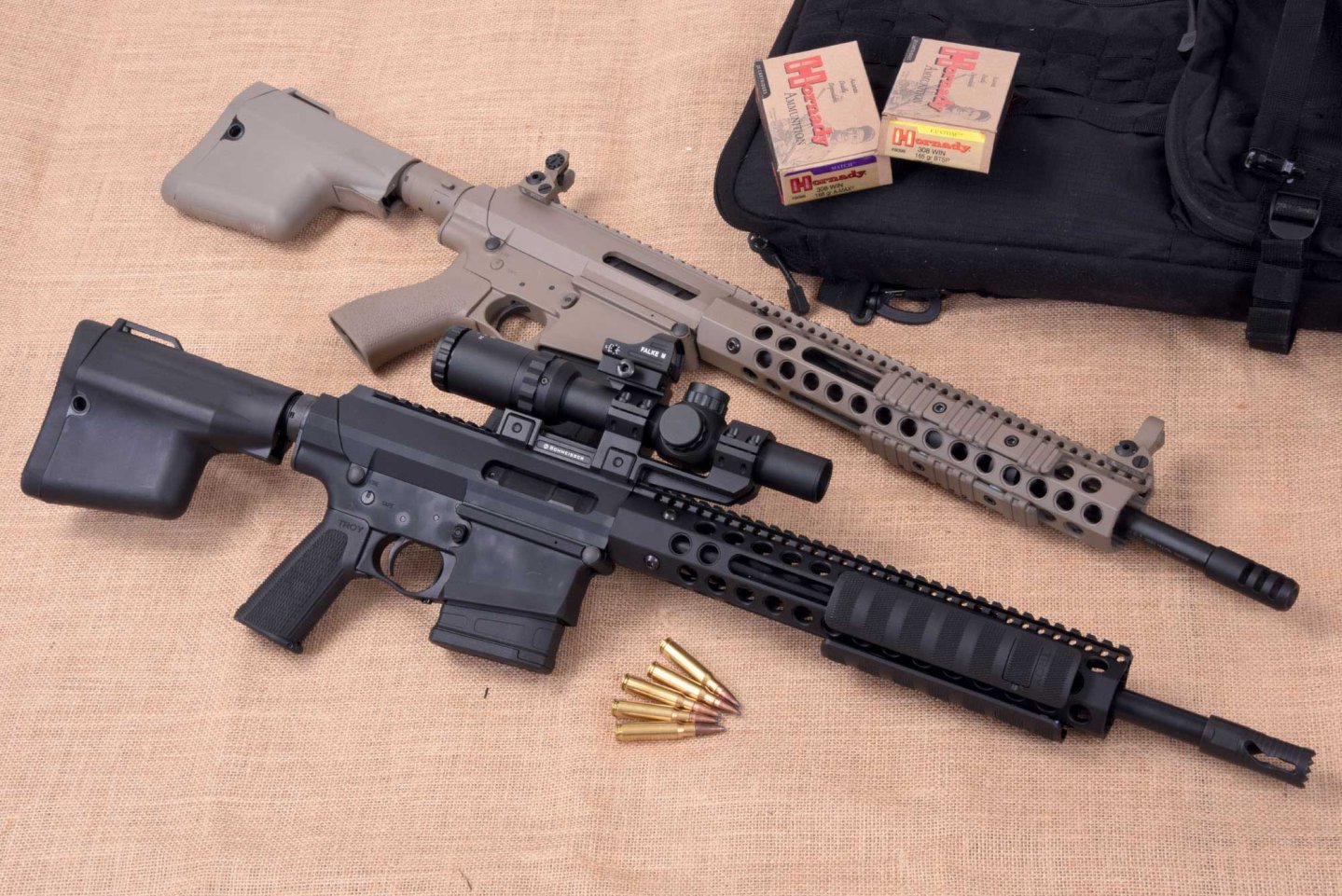 caliber 9/2016 Troy .308 PAR National und Troy .308 PAR Optic Ready auf beigem Hintergrund mit Munition und Munitionsverpackungen.