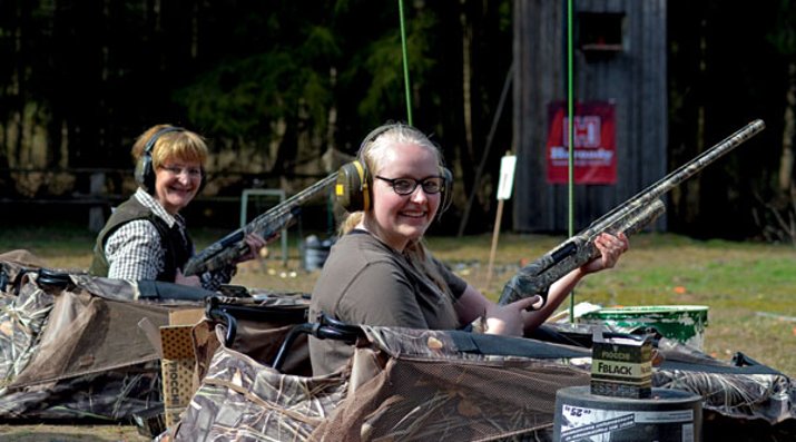 caliber 7+8/2016 Zwei sitzende Schützinnen mit Flinten in der Hand und aufgesetztem Gehörschutz.