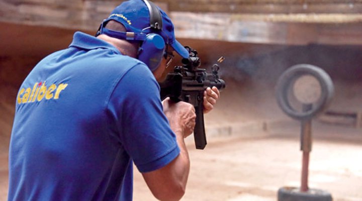 Ein caliber-Tester in blauer Kleidung mit der Heckler & Koch SP 5 K auf dem Schießstand.