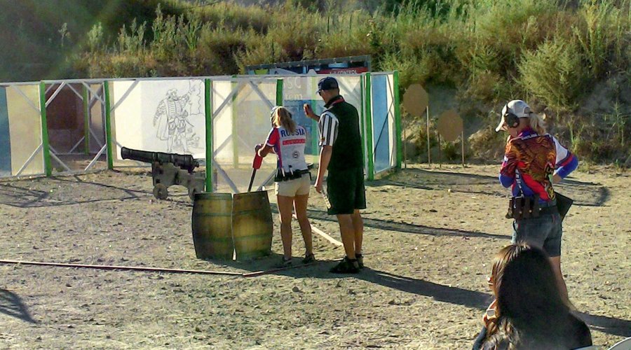 IPSC-Schützin und Schießaufsicht vor Beginn einer ungewöhnlichen Stage mit Kanone beim dynamischen IPSC-Sportschießen