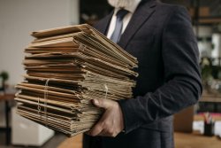 Evaluierung des Waffenrechts 2025: Das sind die Forderungen der Verbände – mit Kommentar Mann trägt einen Stapel Akten.