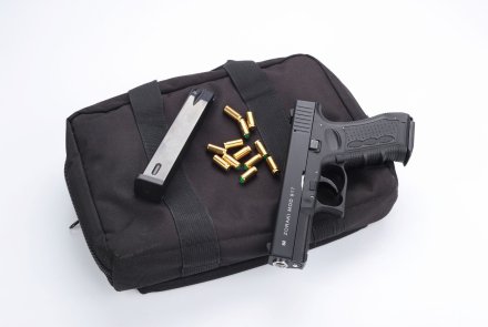 Übersicht Schreckschusswaffen: Gaswaffen in der Praxis und Kleiner Waffenschein Schreckschusspistole auf Waffentasche mit Kartuschenmunition und Magazin.