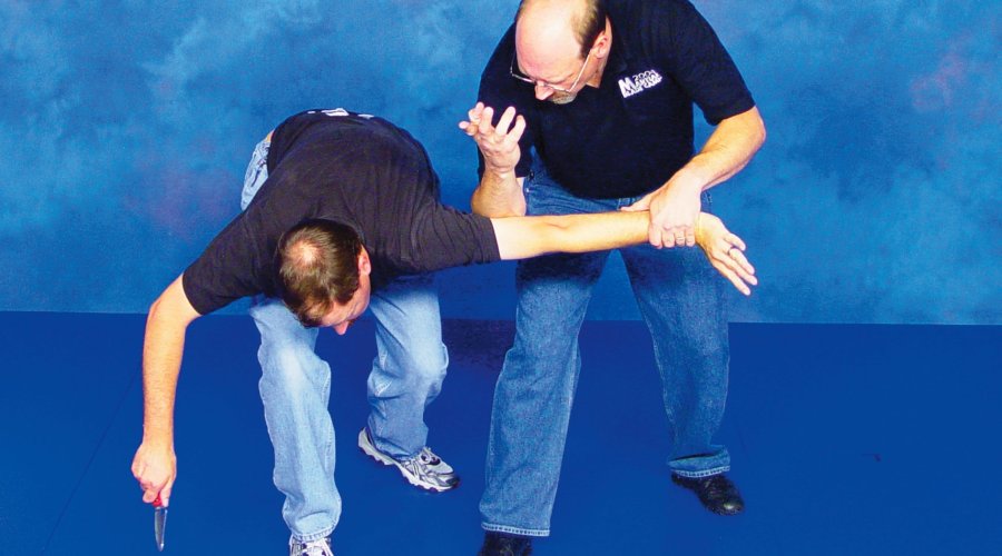 Zwei Männer demonstrieren die Abwehrfolge zur Abwehr eines Messerangriffs mit bloßen Händen.