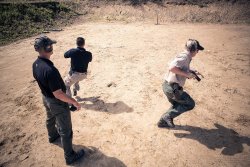 SIG Sauer Academy: Schießübung in Bewegung SIG Sauer Academy Schießübung im Außenbereich. Der Lehrer beobachtet wie zwei erwachsene Schüler eine Übung durchführen.