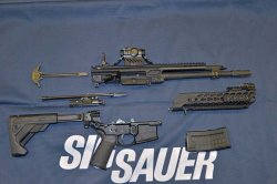 Demontiertes MCX. Man beachte die Laufklemmung am Systemgehäuse. Ein Kaliberwechsel von 5,56x45 mm auf .300 BLK ist durch den Austausch des Laufes ruckzuck bewerkstelligt. Stahlverstärkungen am Steuerstück, Ladehebel und der Zuführrampe erhöhen auch hier die Lebensdauer. Modulares Multikaliber-Sturmgewehr SIG Sauer MCX in Einzelteile zerlegt