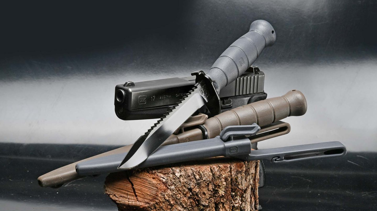 GLOCK Feldmesser: das legendäre Militärmesser des Pistolenherstellers GLOCK Feldmesser: Die Militärmesser FM78 und FM81 liegen auf einem Holzklotz vor einer GLOCK Pistole.