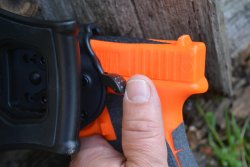 Im Test: Bulldog Thumb Release Polymer Holster von Ferkinghoff International Löseknopf des Holsters mit drauf liegendem Daumen.