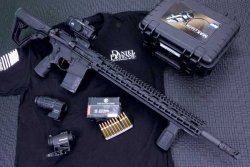 caliber 11+12/2017 Daniel Defense DDM4 V11 Pro in linker Seitenansicht auf T-Shirt mit Zubehör.