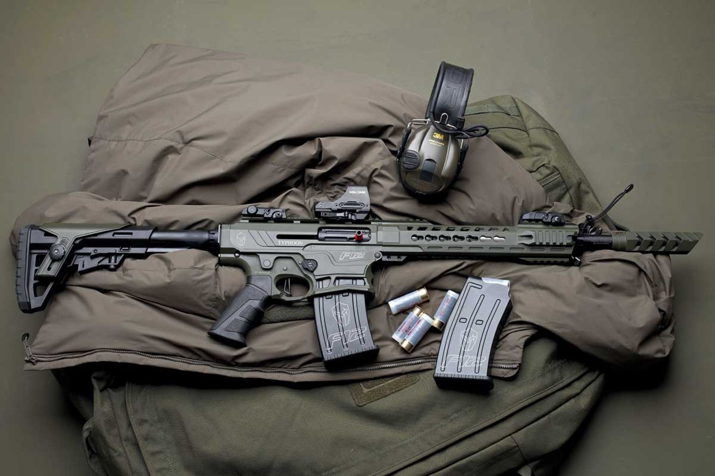 caliber 11+12/2017 Typhoon Defence Industries F-12 in 12/76 in olivgrün mit Holosun Leuchtpunktvisier HS510C auf olivgrüner Jacke.