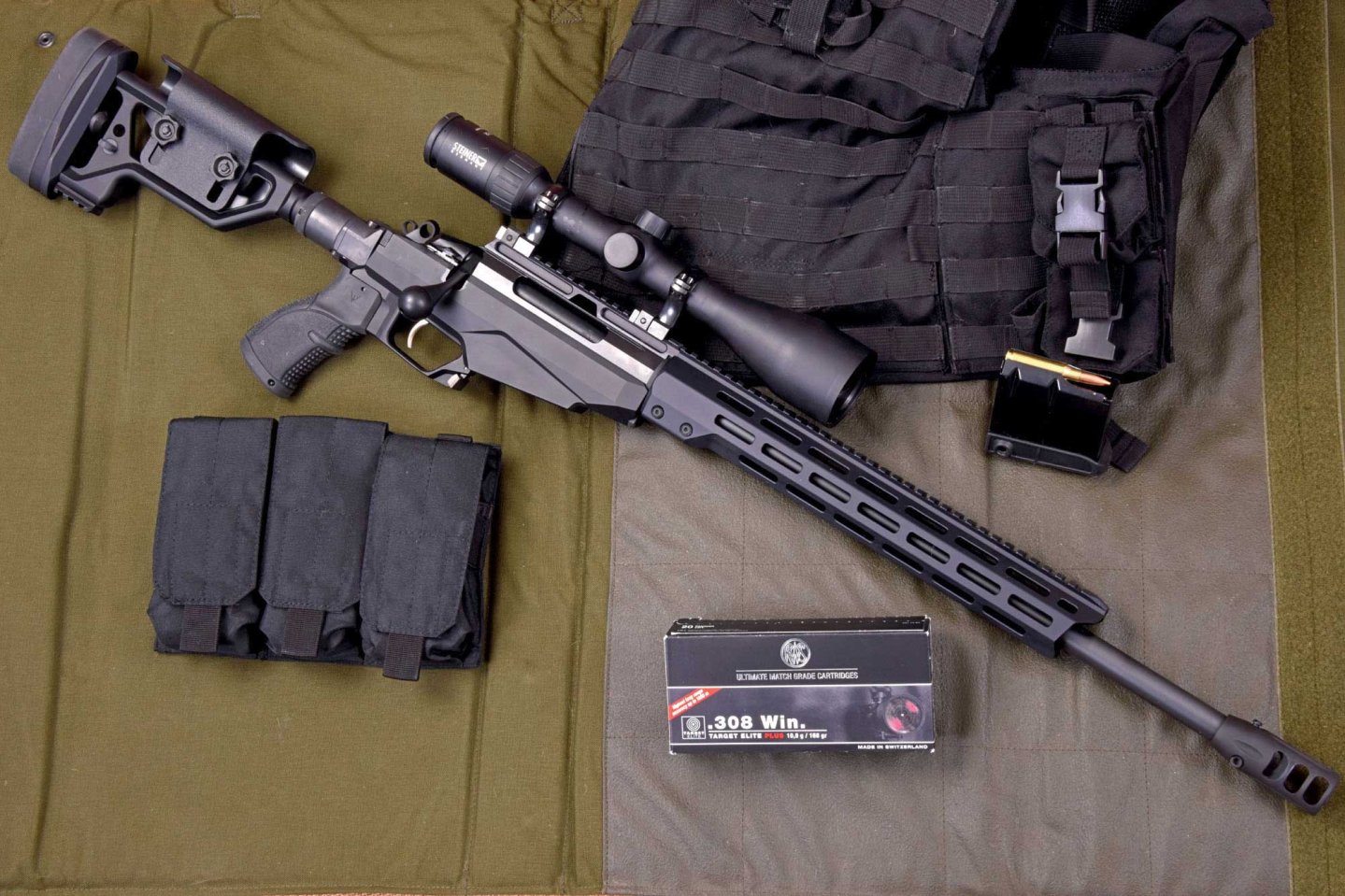 caliber 6/2017 Tikka T3x TAC A1 in rechter Seitenansicht. Mit Patronenpackung und Zubehör.