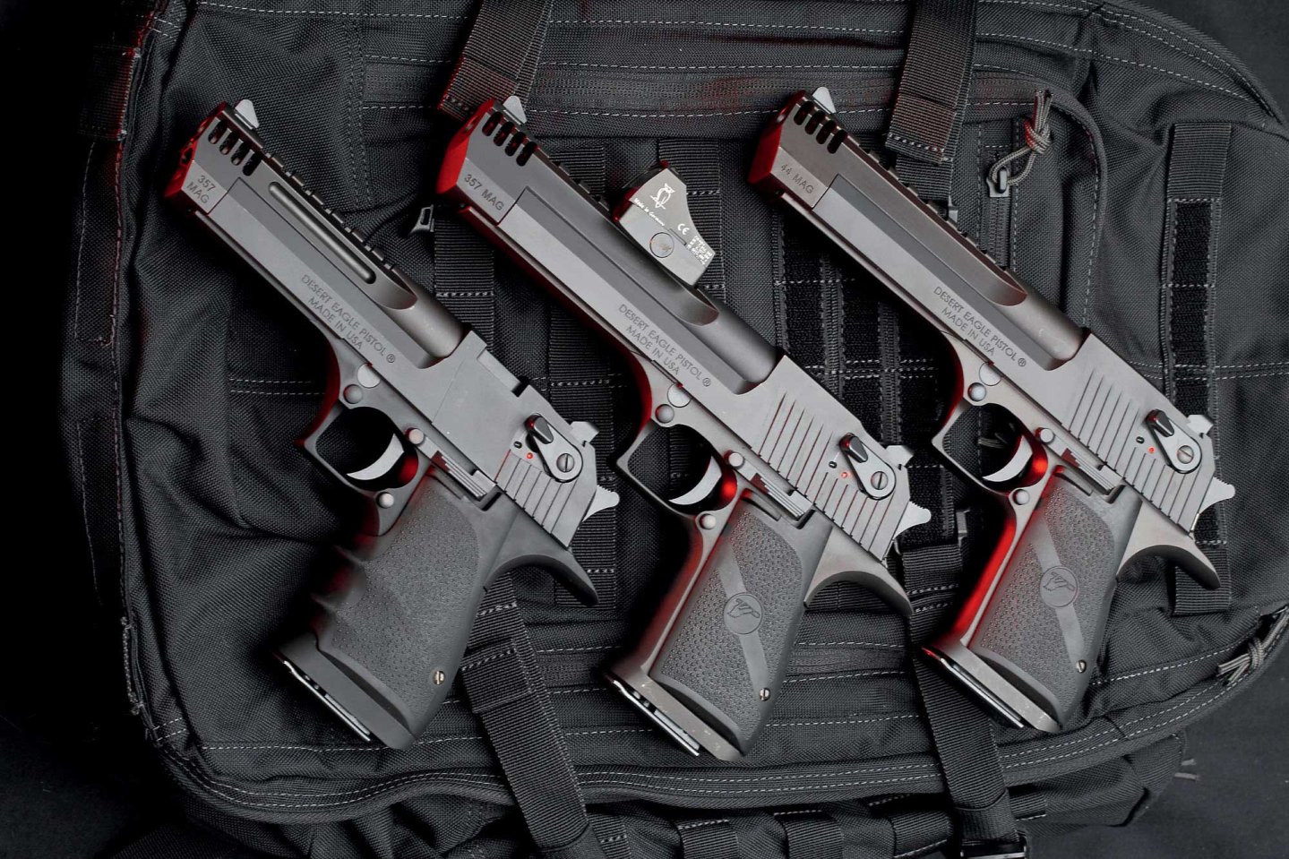 Drei Desert Eagle in linker Seitenansicht auf einem schwarzen Rucksack.