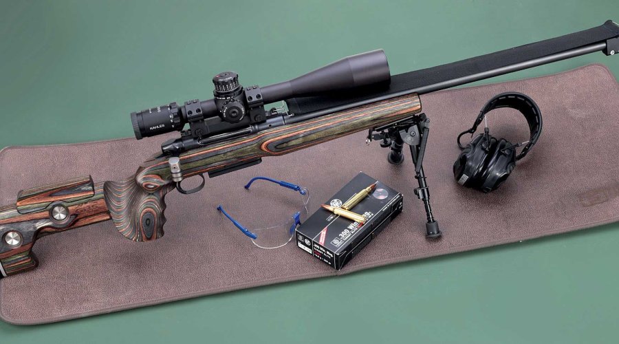 Heym SR30 Precision auf dunkelbrauner Schießmatte mit Munition, Brille und Gehörschutz.