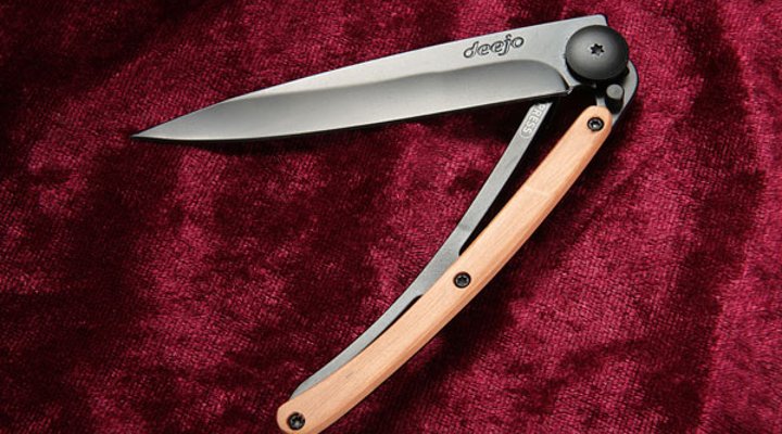 halbgeöffnetes Deejo Black mit Wacholderholz auf rotem Samt