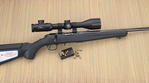 VISIER 6/2016 Ruger American Rimfire in rechter Seitenansicht auf Bastmatte mit Munition und aufgesetztem Zielfernrohr GECO 2,5-15x50 IR und großem Aufkleber auf dem Schaft.