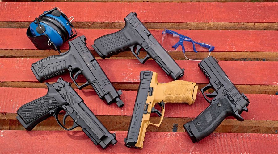 Fünf Selbstladepistolen auf rotem Holz mit Hörschutz und Schießbrille.