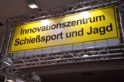 Innovationszentrum Schießsport und Jagd - jetzt auf über 100 m² Traversengerüst mit gelbem Schild und dem Aufdruck "Innovationszentrum Schießsport und Jagd"