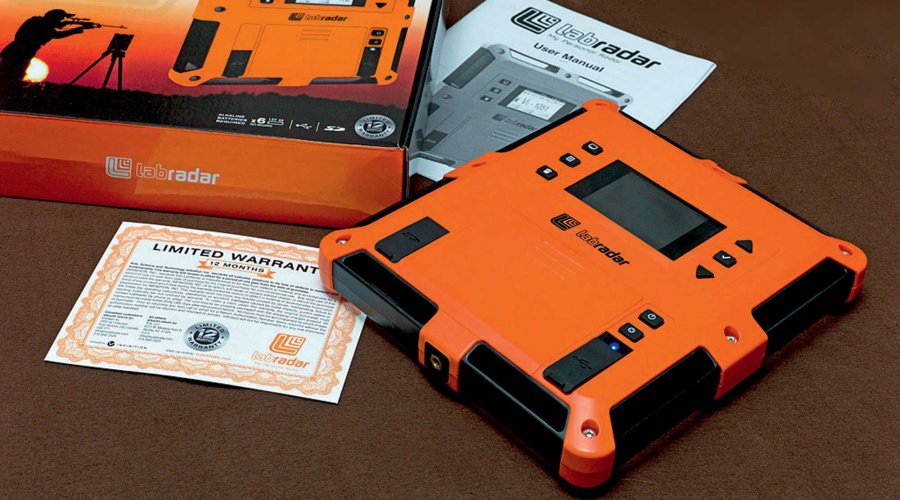 LabRadar mit Verpackung und Anleitungen auf braunem Untergrund.