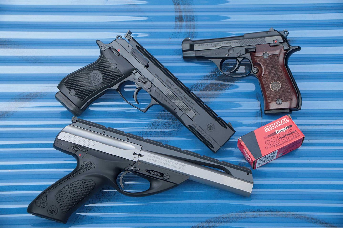 Beretta 87 Cheetah (oben), 87 Target (mitte) und Neos (unten) auf blauem gewellten Hintergrund.