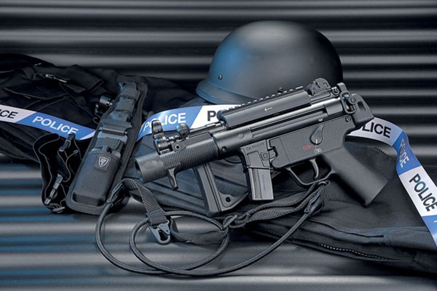 VISIER 7/2016 Heckler & Koch SP 5 K in linker Seitenansicht mit eingeklappter Schulterstütze auf schwarzem Range Bag und Helm.