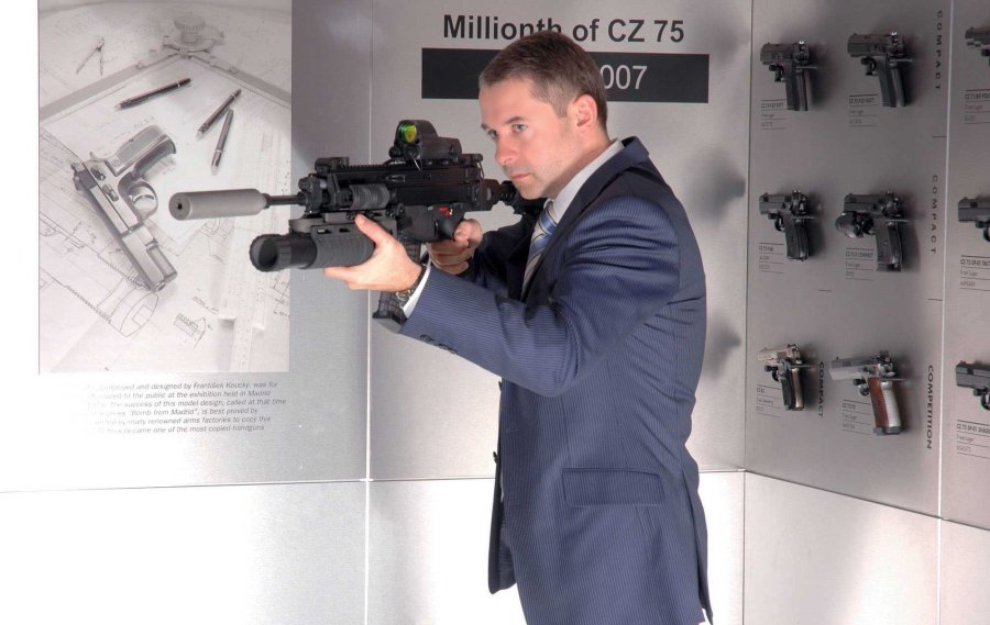 VISIER 8/2016 CZ-Chef Lubomir Kovarik mit einer CZ 805 Bren vor einer Wand mit mehreren CZ-Pistolen.