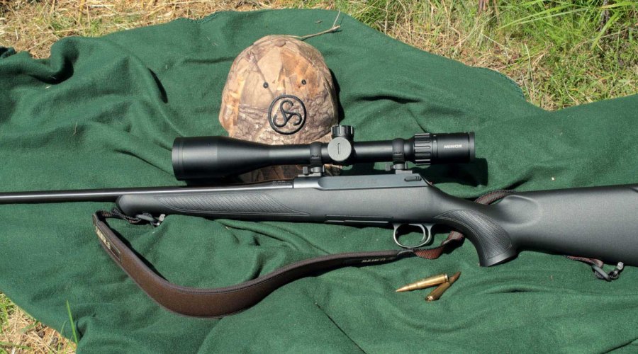 Die Sauer S 100 mit Optik und .308-Winchester-Patronen auf eine grünen Decke auf einer Wiese.