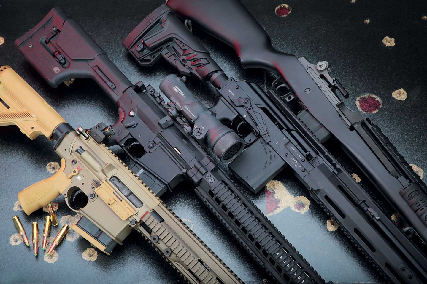 Heckler & Koch MR 308 A3, Oberland Arms OA-10, Molot Vepr V1TAC und LuxDefTec M14 SOCOM in .308 Winchester auf schwarzem Hintergrund mit Einschusslöchern.
