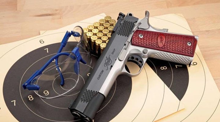 Kimber Grand Raptor II in linker Seitenansicht mit Zielscheiben, Schießbrille und Munition.