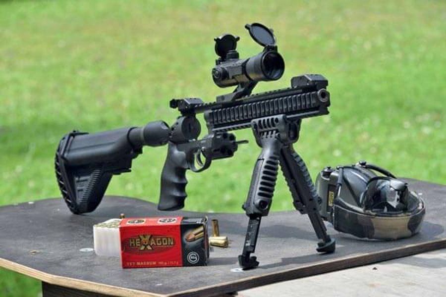 VISIER 10/2017 Korth Wheel Hunter von schräg vorne auf einer Holzplatte mit Munition und Gehörschutz. Im Hintergrund eine Wiese.