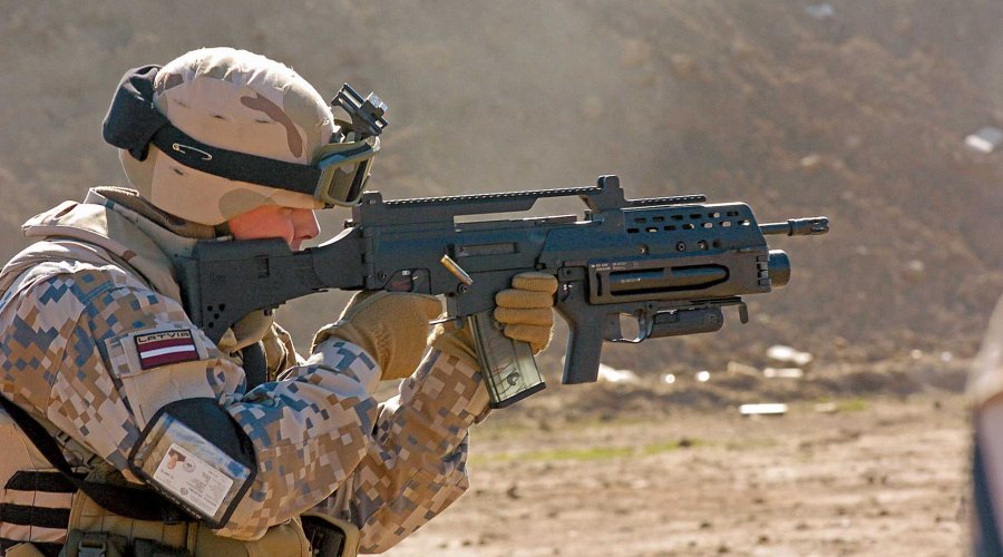 Lettischer Soldat in Wüstenregion mit G36 im Kniend-Anschlag.