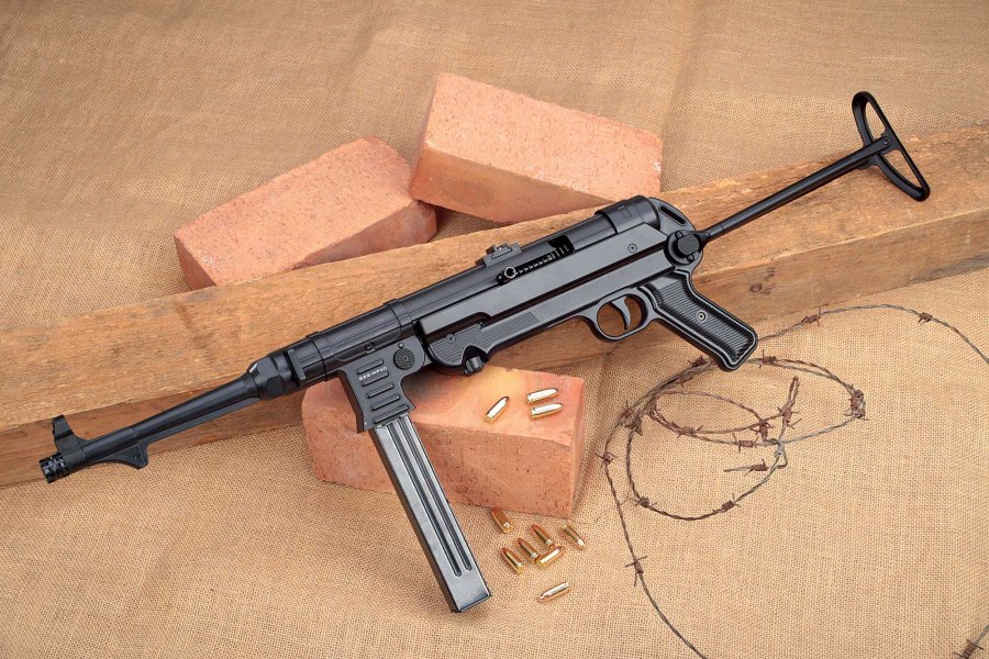 VISIER 11/2016 GSG MP 40 in linker Seitenansicht auf Holzbalken, Ziegeln und Stacheldraht mit 9 mm Luger-Munition.