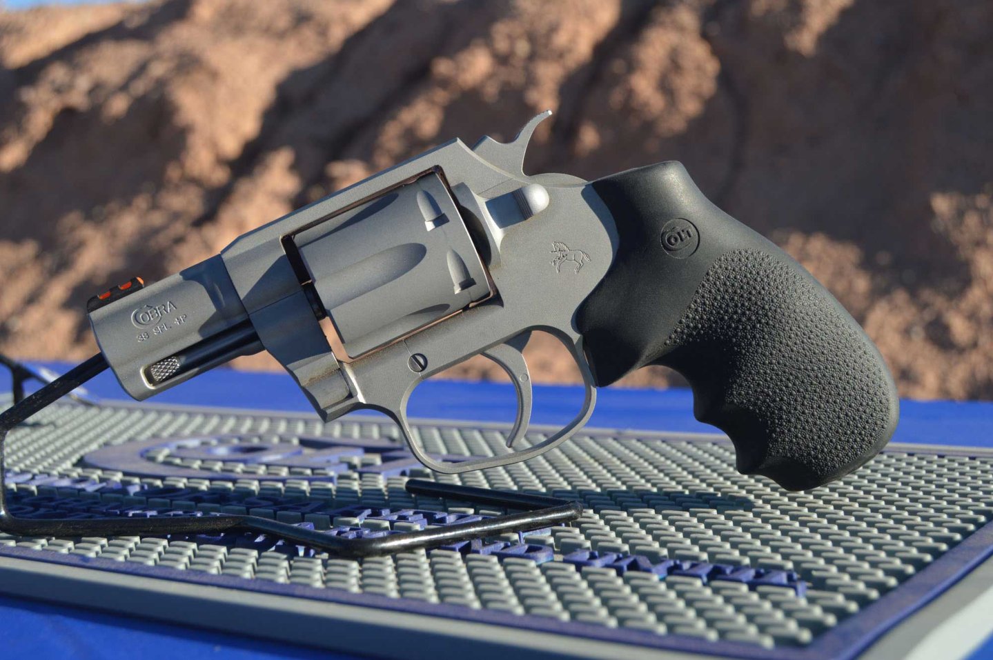 Colt Cobra in linker Seitenansicht auf Pistolenständer vor Felsem.