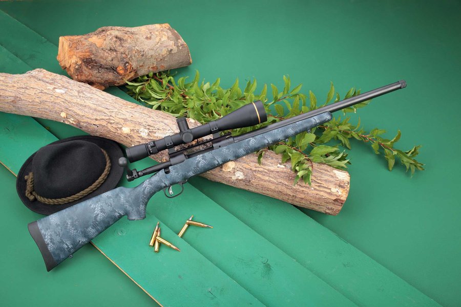 VISIER 9/2017 Savage 10T-SR in rechter Seitenansicht auf einem Baumstamm und grünen Brettern mit Hut, Munition und Laub.